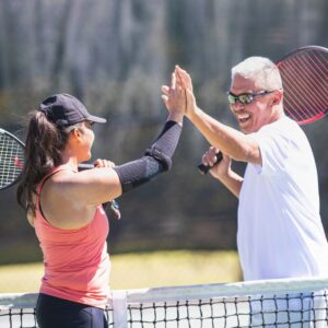 people high fiving on a tennis court