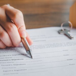 Person pointing to a signature section on a form with a pen