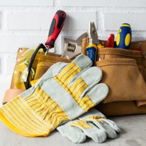 A pair of work gloves next to a tool bag with tools