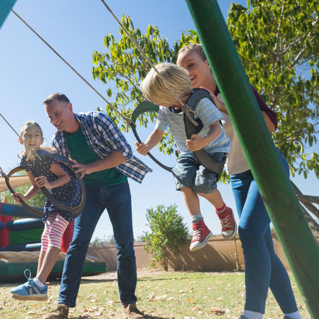 parents pushing kids on swings