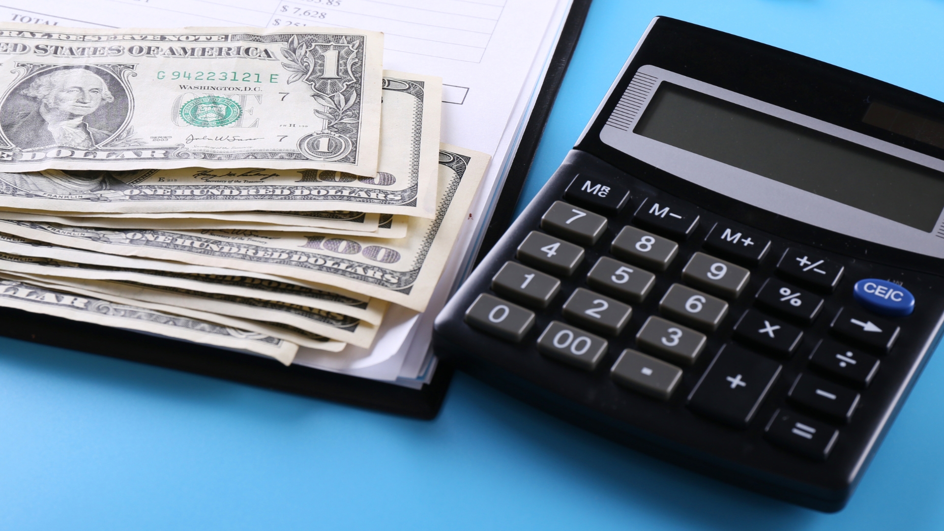 Calculator next to stack of dollar bills